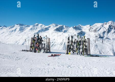 Skier und Snowboards auf Regalen vor dem Skirestaurant mit schneebedeckten Bergen dahinter, Hochgurgl, Tirol, Österreich Stockfoto