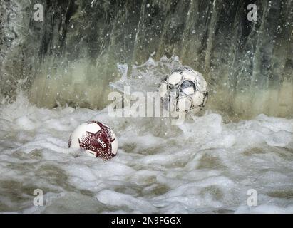 20. April 2021, Hessen, Frankfurt/Main: Fußbälle tanzen auf dem Wasser an einem Wehr auf dem Fluss Nidda, wo sie im Wasser gefangen werden. Der kleine Fluss fließt vorbei an zahlreichen Sportplätzen und Freizeiteinrichtungen im Norden Frankfurts und den benachbarten Städten, von wo aus immer wieder Bälle ins Wasser fallen. Foto: Frank Rumpenhorst/dpa/Frank Rumpenhorst/dpa Stockfoto