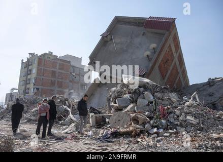 Kahramanmaras, Türkei. 12. Februar 2023. Die Menschen gehen an den Häusern ihrer Nachbarschaft vorbei, die durch das Erdbeben zerstört wurden. Fast eine Woche nach der Erdbebenkatastrophe in der türkisch-syrischen Grenzregion ist die Zahl der Toten auf über 30.000 gestiegen. Kredit: Boris Roessler/dpa/Alamy Live News Stockfoto