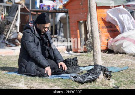 Kahramanmaras, Türkei. 12. Februar 2023. Ein Mann betet im Garten eines Hauses. Fast eine Woche nach der Erdbebenkatastrophe in der türkisch-syrischen Grenzregion ist die Zahl der Toten auf über 30.000 gestiegen. Kredit: Boris Roessler/dpa/Alamy Live News Stockfoto