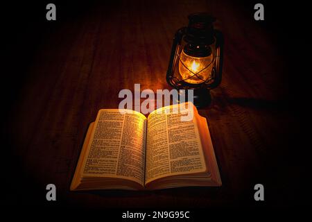 Ein offenes Buch und eine alte Lampe auf einem Tisch Stockfoto