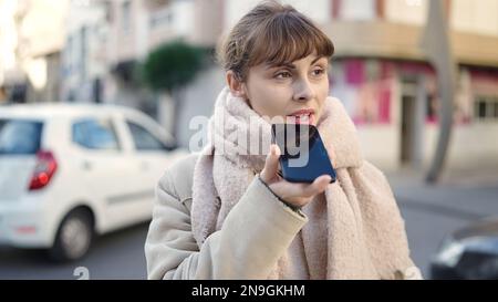 Junge weiße Frau, die eine Sprachnachricht auf der Straße aufnimmt Stockfoto