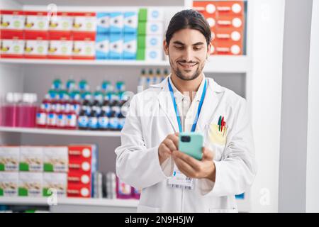 Junger hispanic-Mann Apotheker mit Smartphone in der Apotheke arbeiten Stockfoto