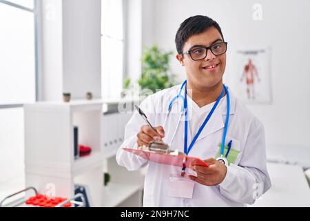 Down-Syndrom-Mann in Arztuniform auf Dokument in der Klinik Stockfoto