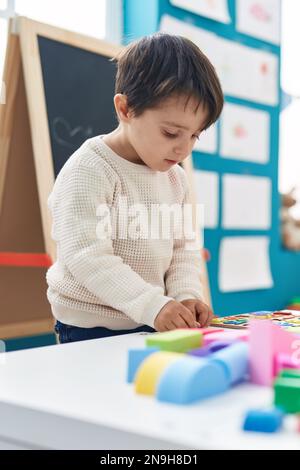 Ein bezaubernder spanischer Junge, der im Kindergarten mit einem Mathe-Puzzle spielt Stockfoto