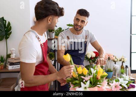 Zwei hispanische Blumenhändler, die selbstbewusst lächeln, machen einen Blumenstrauß im Blumenladen Stockfoto