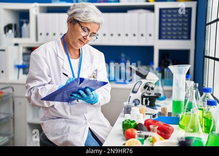 Eine Frau mittleren Alters, die Uniform trägt und im Labor auf einem Dokument schreibt Stockfoto