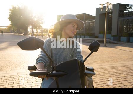 Frau Tourist Reiten ein vier Rad Mobilität Elektroroller auf einer Stadtstraße. Stockfoto