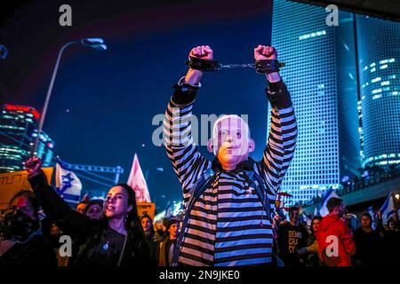 Tel Aviv, Israel. 11. Februar 2023. Ein israelischer Demonstrant, der als Gefangener verkleidet ist und eine Maske trägt, die aussieht wie Premierminister Benjamin Netanjahu, hält während eines Protests gegen den Justizreformplan der Regierung seine Handschellen hoch. In der sechsten Woche in Folge meldeten sich über 160000 Menschen in Israel gegen kontroverse Rechtsreformen, die von Benjamin Netanjahus rechtmäßiger Regierung angepreist wurden. (Foto: Eyal Warshavsky/SOPA Images/Sipa USA) Guthaben: SIPA USA/Alamy Live News Stockfoto