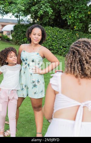 Lateinische Mutter macht ein Handyfoto ihrer Töchter im Freien Stockfoto