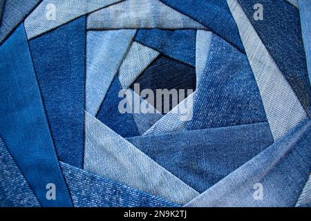 Das neue Leben alter Jeans. Alte Kleidung recyceln. Jeansdecke als Kissen in der Crazy-Rose-Technik. Jeans-Hintergrund, Flickentextur. Stockfoto