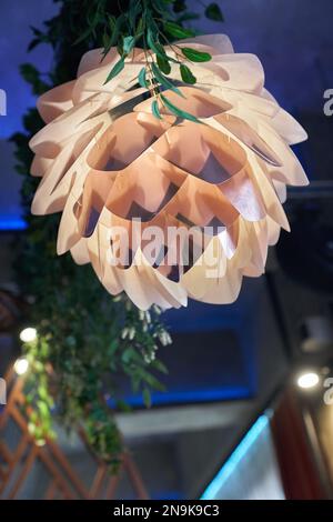 Ein Kronleuchter in Form einer Lotusblume, von der Decke aufgehängt und mit Licht beleuchtet. Das Konzept der Inneneinrichtung des Restaurants. Selektiver Fokus mit Platz zum Kopieren.Fotos in hoher Qualität Stockfoto