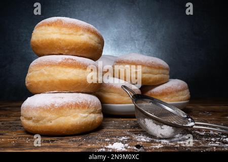 Polnische, frittierte pączki-Donuts. Fat Thursday Tłusty Czwartek traditionelles Festmahl in Polen. Pączek Lebensmittel mit Puderzucker und Marmelade. Stockfoto