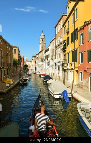 Von oben aus haben Sie einen Blick auf eine Gondel auf dem Kanal Rio de San Barnaba mit dem Glockenturm der Kirche Santa Maria dei Carmini, Venedig, Veneto, Italien Stockfoto