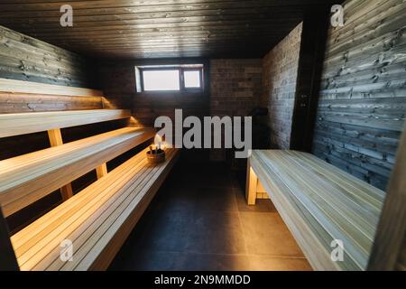 Moderne Innenausstattung der Spa-Hütte aus Holz. Blick auf den leeren finnischen Saunaraum mit Trockendampf. Neu und frisch Stockfoto
