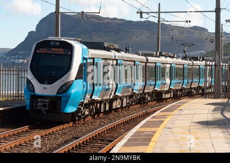 Bahnhof St. James, Westkap, Südafrika. 2023. Ein neuer blauer Zug, der Volkszug, fährt vom Bahnhof St. James auf der Küstenstraße nach Fish Hoek Ca Stockfoto