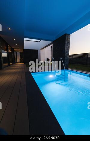 Tauchbecken mit kaltem Wasser, das nach dem Entspannen in der Sauna zubereitet wird. Der Pool ist mit Wasser gefüllt. Abendfoto mit Hintergrundbeleuchtung Stockfoto
