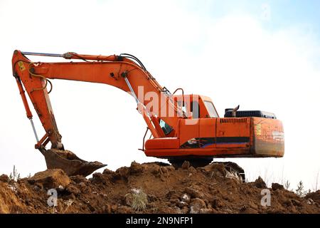 Der Raupenbagger schaufelt die Erde mit einem Löffel. Erdbewegungsarbeiten, Grabarbeiten und Bauindustrie Stockfoto