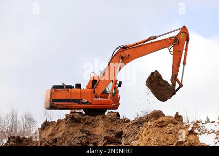 Der Raupenbagger schaufelt die Erde mit einem Löffel. Erdbewegungsarbeiten, Grabarbeiten und Bauindustrie Stockfoto