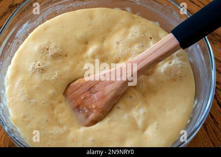 Vorspeise für die Zubereitung von Brotteig. Teig in einer Schüssel mit einem Holzlöffel auf dem Tisch. Blasen im Teig aus fermentierter Hefe. Stockfoto