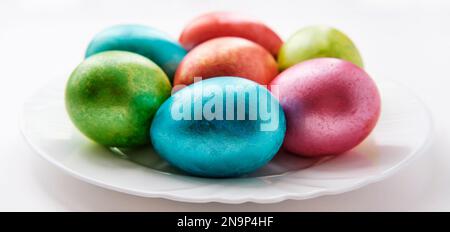 Mehrfarbige Eier auf weißem Teller Stockfoto