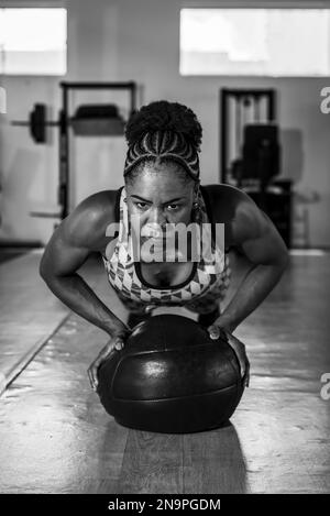 Entschlossene Frau, die mit einem Ball im Fitnessstudio Unterstützung leistet. Wirbelsäule und Arme stärken. Stockfoto