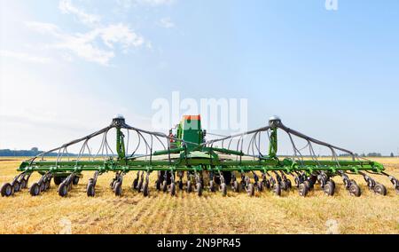 Moderne landwirtschaftliche Pflanzmaschine auf einem gelben Feld vor einem blauen bewölkten Himmel an einem Sommertag. Speicherplatz kopieren. Nahaufnahme. Stockfoto