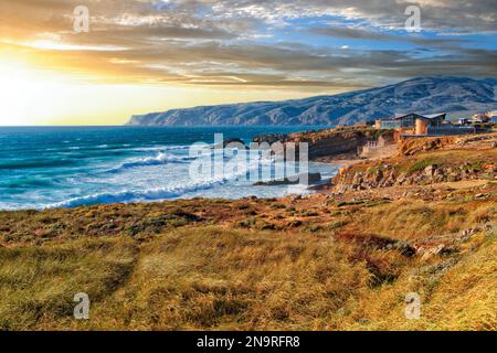 Malerische Sonnenuntergangslandschaft am felsigen Ufer des wütenden Atlantischen Ozeans in der Nähe von Cape Roca im Licht der untergehenden Sonne Portugals. Gemeinde Stockfoto