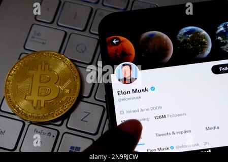 In dieser Fotoabbildung wird Elon Musks twitter-Konto auf einem Smartphone neben einer Bitcoin angezeigt. Stockfoto