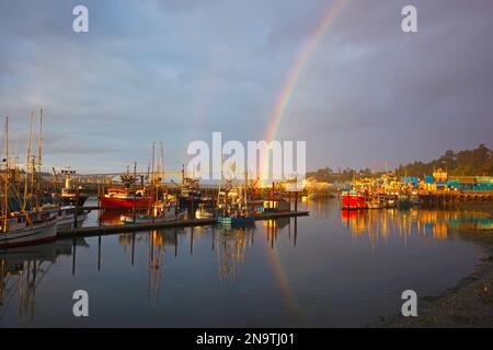 Regenbogen im Morgenlicht über der Yaquina Bay Bridge und Fischerboote im Hafen; Newport, Oregon, Vereinigte Staaten von Amerika Stockfoto