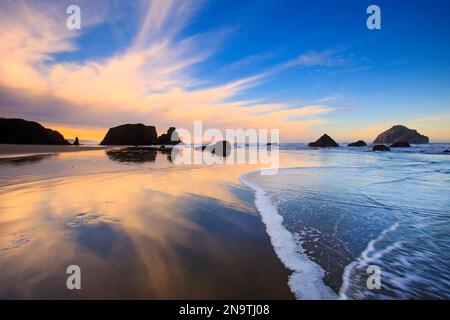 Silhouetten von Felsformationen am Bandon Beach bei Sonnenaufgang bei Ebbe an der Küste Oregons; Oregon, Vereinigte Staaten von Amerika Stockfoto