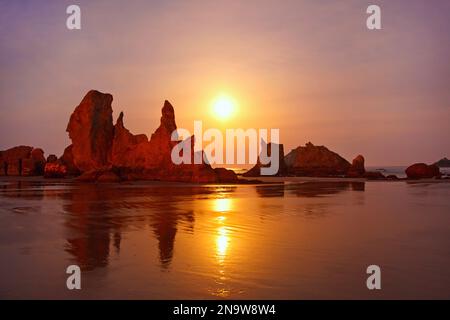 Silhouetten von Felsformationen am Bandon Beach bei Sonnenuntergang bei Ebbe an der Küste Oregons; Oregon, Vereinigte Staaten von Amerika Stockfoto