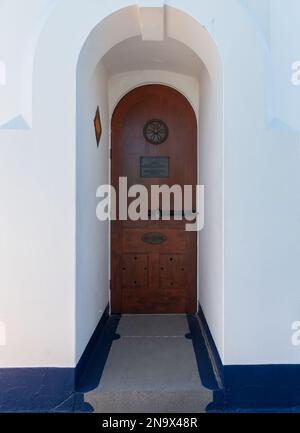 Alte Holztür mit Schloss und Schloss in einer gewölbten Veranda. Stockfoto