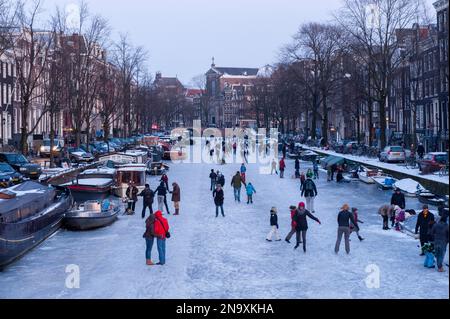 Zahlreiche Menschen, die auf den Kanälen Schlittschuhlaufen; Amsterdam, Niederlande Stockfoto