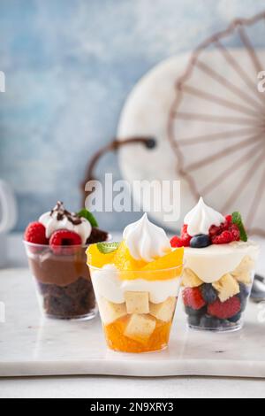 Auswahl an kleinen Desserts in Tassen, Schokolade, Beeren und Orangen Kleinigkeiten oder Parfaits Stockfoto