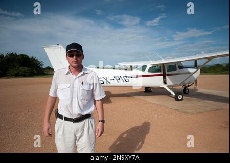 Ein Pilot steht in der Nähe seines Flugzeugs auf einer Landebahn, Uganda Stockfoto