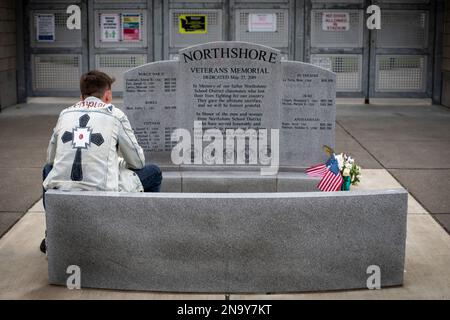 Der junge Mann sitzt in einer Gedenkstätte für amerikanische Kriegsveteranen in Bothell, Washington, Vereinigte Staaten von Amerika Stockfoto