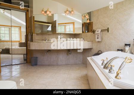 Hauptbadezimmer mit Whirlpool und beigefarbenem Keramikfliesenboden und Arbeitsplatte im Inneren des Piece sur Piece östliche, weiße Kiefernholz und Holzhaus. Stockfoto