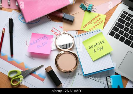 Unordentlicher Tisch mit Laptop und Kosmetik, flach liegend. Das Konzept, von der Arbeit überfordert zu werden Stockfoto