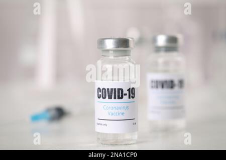 Fläschchen und Spritze mit Coronavirus-Impfstoff auf dem Lichttisch Stockfoto