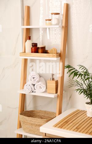 Weiche Handtücher und verschiedene Toilettenartikel auf der dekorativen Leiter im Badezimmer. Innendesign Stockfoto