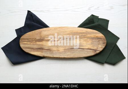 Leeres Holzbrett und Servietten auf weißem Tisch, Draufsicht Stockfoto