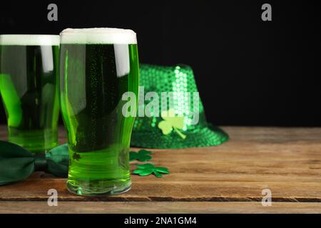 Grünbier und St. Patrick's Day-Einrichtung auf Holztisch vor schwarzem Hintergrund. Platz für Text Stockfoto