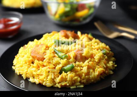 Köstlicher Reispilaf mit Fleisch auf schwarzem Teller, Nahaufnahme Stockfoto