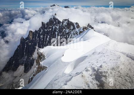 Kletterer verlassen Aiguille du Midi. Der Gipfel von Aiguille du Plan ist im Hintergrund. Chamonix - Mont Blanc, Alpen, Frankreich, Europa, Sommer. Stockfoto