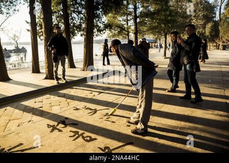 Mann, der übergroße Kalligraphie auf dem Boden schreibt, Sommerpalast, Peking, China © Dosfotos/Axiom Stockfoto