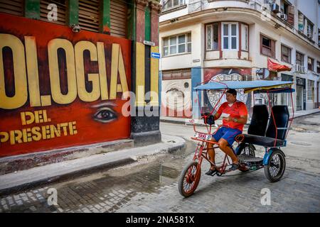 Ein Mann, der auf einem Fahrradtaxi auf den Straßen von Havanna, Havanna, Kuba fährt Stockfoto