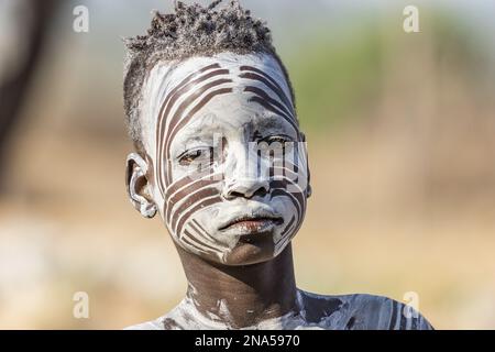 Junger Karo-Mann, der sein Gesicht mit traditioneller Gesichtsfarbe im Dorf Kortcho, Omo Valley, Äthiopien, dekoriert hat Stockfoto