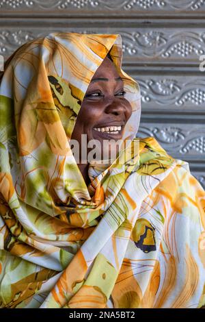 Porträt einer sudanesischen Frau mit einem großen Lächeln und farbenfrohem Kopftuch; Dongola, Nordstaat, Sudan Stockfoto