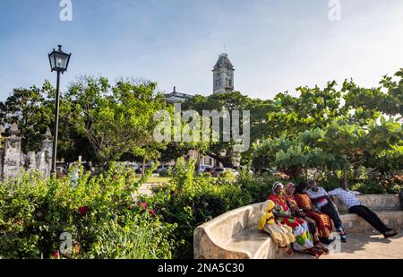 Menschen sitzen auf einer Bank in Forodhani Gardens, Steinstadt Sansibar; Sansibar City, Unguja Island, Sansibar, Tansania Stockfoto